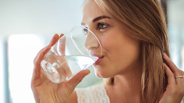 woman drinking water from glass cup