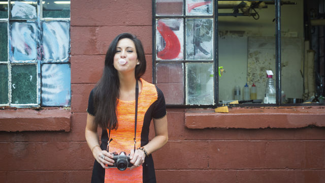 Woman blowing a bubble with chewing gum and holding a camera
