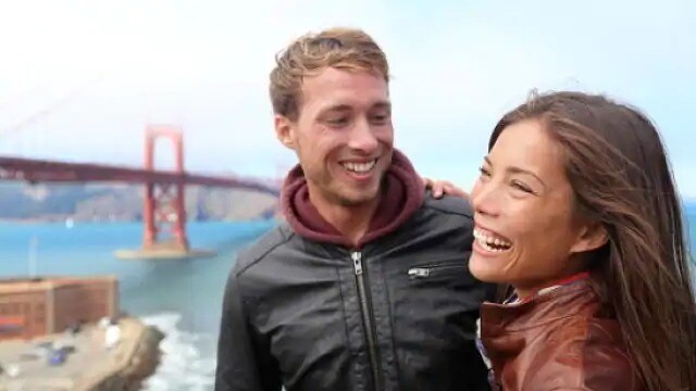 young couple smiling near a bridge