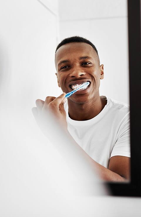 man brushing teeth in mirror with Colgate toothbrush man brushing teeth in mirror with Colgate toothbrush