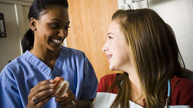 dental hygienist and patient looking at a mouth model dental hygienist and patient looking at a mouth model