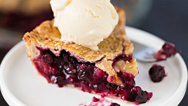 A slice of sweet berry pie and ice cream on a top A sweet berry pie and ice cream on a top