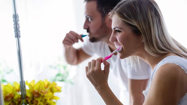couple brushing teeth together couple brushing teeth together