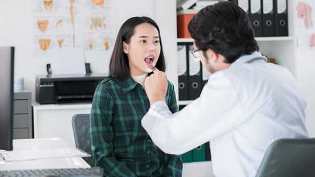 The doctor is examining young patient's oral cavity and lips